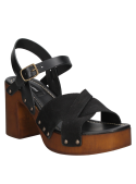 Remaches metálicos en las costuras de sandalia negra de cuero, resaltan un estilo industrial o bohemio.