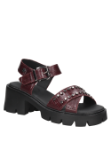 Sandalia estilo chunky burdeos con suela prominente y detalles metálicos, adecuada para atuendos casuales y urbanos.