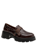 Mocasín de cuero café para mujer con diseño de tachas y patrón reptil, elegante y moderno con detalles metálicos.