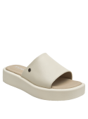 Sandalia beige de cuero para mujer combinada con jeans rectos, mostrando un look casual relajado.