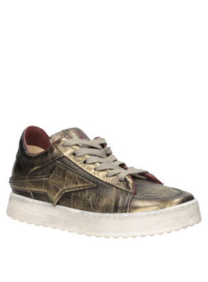 Zapatilla de mujer en cuero suave dorado, perfecta para combinar con jeans ajustados y blusas elegantes.